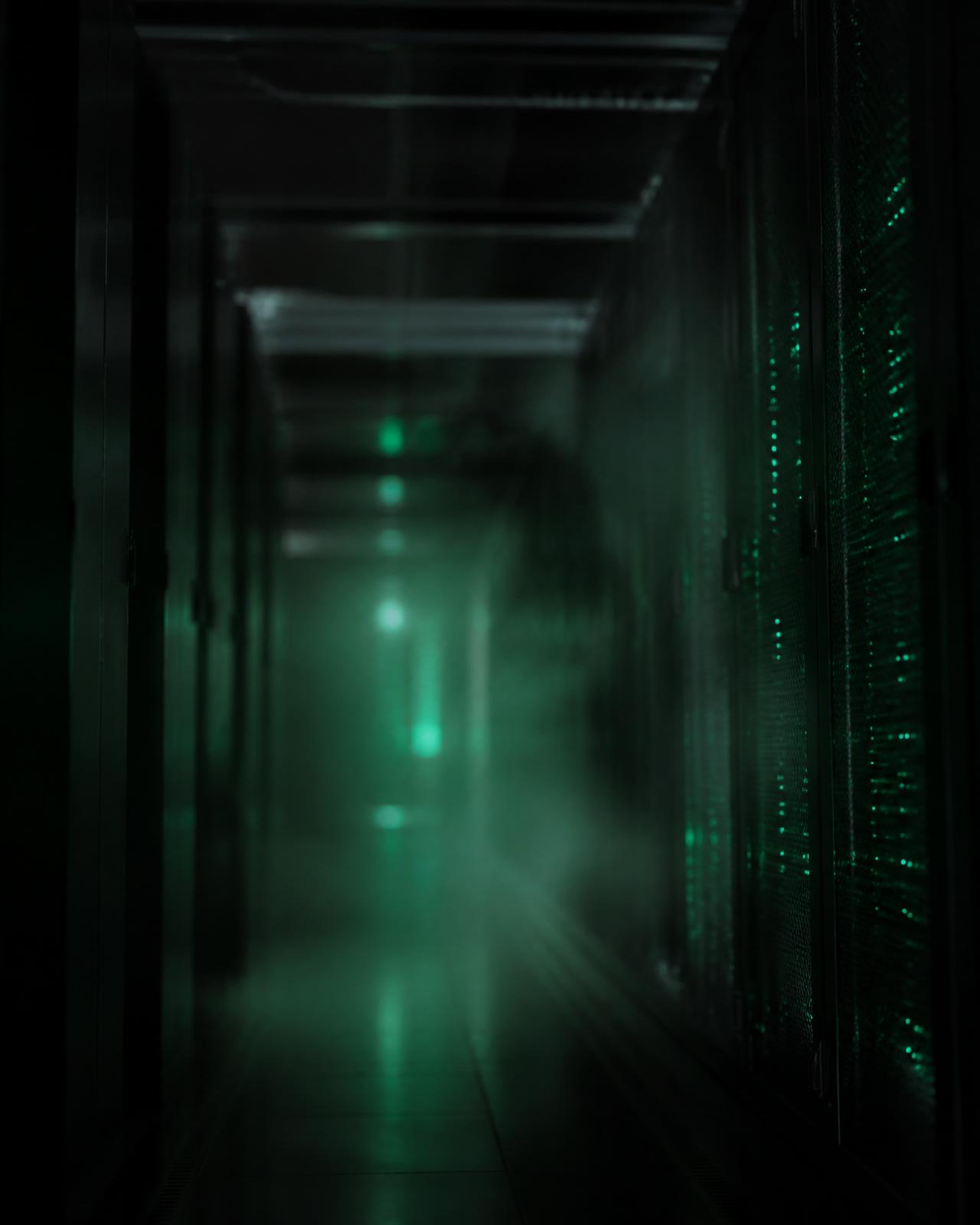 Dimly lit enterprise data centre corridor, deliberately obscured